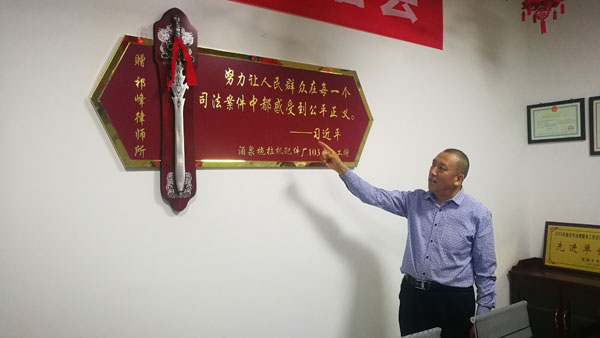 在甘肃祁峰律师事务所会议室正中，挂着一副特别的“锦旗”，是由一柄剑和金属框制作的匾牌，匾牌上金色大字书写习近平总书记的一句话：努力让人民群众在每一个司法案件中都感受到公平正义?！迫侠浼В保? title=